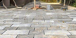 Laying concrete paving stones. Paving the driveway. Paving utensils visible in the background.