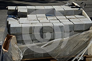 Laying granite and marble light, white gray, medium size cubes. tilers put cobblestones in sand or gravel. they have piles ready photo