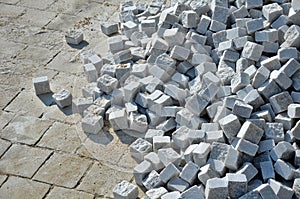 Laying granite and marble light, white gray, medium size cubes. tilers put cobblestones in sand or gravel. they have piles ready t photo