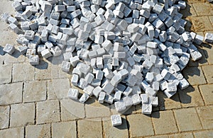 Laying granite and marble light, white gray, medium size cubes. tilers put cobblestones in sand or gravel. they have piles ready t photo