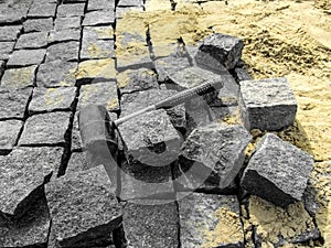 Laying granite paving stones - building background with copy space. A black rubber mallet lies among gray rectangular blocks of