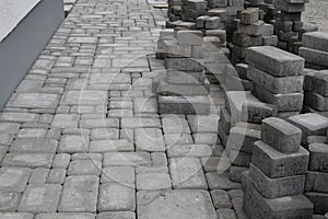 Laying gray concrete paving slabs in a house walkway om yard.