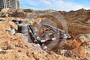 Laying heating pipes in trench at construction site. Installing concrete sewer wells and underground storm systems of sanitary photo