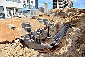 Laying heating pipes in trench at construction site. Installing concrete sewer wells and underground storm systems of sanitary