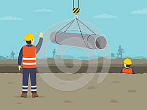 Laying and joining of water supply pipes. Lifting operations in construction. The worker shows stop gesture.
