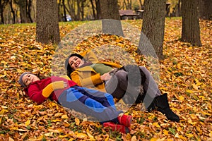 Laying mother,son and dog in autumn leaves