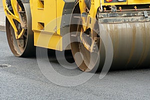 Laying of new modern asphalt. Asphalt laying equipment works on the site. A yellow asphalt skating rink rides in close-up on a new