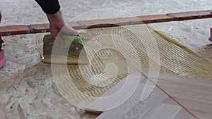 Laying parquet in an apartment during renovation. Herringbone parquet video 4k. Worker installing wood parquet