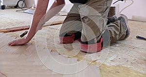 Laying parquet in an apartment during renovation. Herringbone parquet video 4k. Worker installing wood parquet