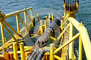 Laying of pipes with pipe-laying barge crane near the shore. Descent of the pipeline to a bottom exhausting with the pipelaying