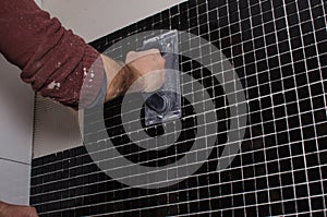 laying a tile black mosaic hands master