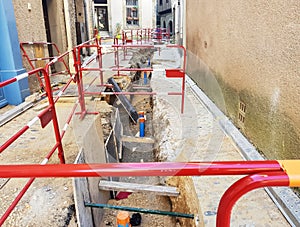 The laying of underground communications cables in a narrow street of a European medieval city