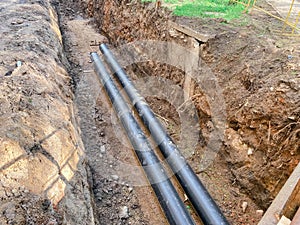 Laying of underground communications for residential buildings. plumbing pipes of black color are buried deep in an earthen ditch