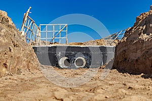 Laying of underground pipes in concrete chamber. Installation of water main at the construction site. Construction of stormwater