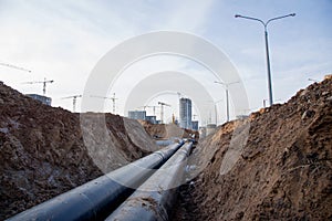 Laying of underground storm sewer pipes at the construction site. Installation of water main and sanitary sewer on background