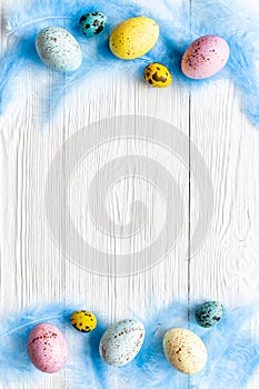 Layout of colorful Easter eggs and birds feather, top view
