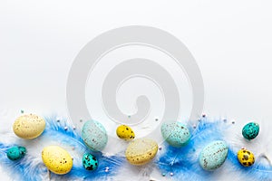 Layout of colorful Easter eggs and birds feather, top view