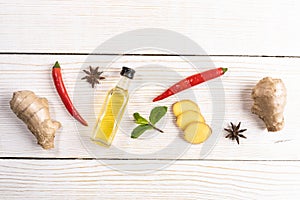 Layout of condiments with ginger and ginger oil on light wooden background.