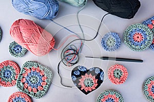 Layout of crochet patterns, a hook, a heart and yarns around on grey background