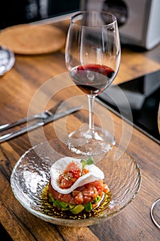 The layout of the finished dish. Tuna tartar on a plate and a glass of red wine. Master class in the kitchen. The process of