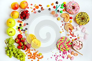 Layout of fruits, berries and multi-colored sweets on a white background. Contrasting healthy and unhealthy food. Top view