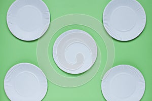 The layout on a green background from paper disposable plates. Caring for the environment. Recycling and sorting of garbage.