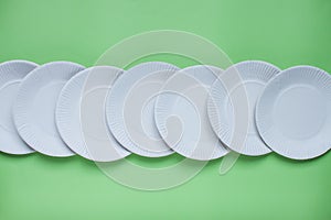 The layout on a green background from paper disposable plates. Caring for the environment. Recycling and sorting of garbage.