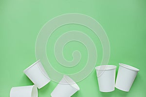 The layout on a green background from white paper disposable cups. Caring for the environment. Recycling garbage