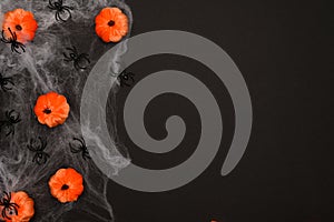 Layout of Halloween decorations on a black background: pumpkins,in a cobweb,spiders, top view. Flat layout.Arachnophobia