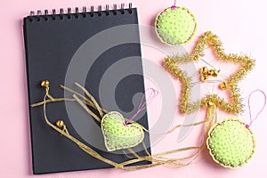Layout for holiday to-do list. black notebook, star of tinsel and felt toys on pink background. flat lay, copy space, minimal