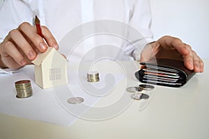 Layout of a house made of white paper and a woman& x27;s hand, a calculator on a white table. The concept of a mortgage.