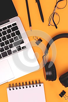 Layout with laptop, headphones and stationery on a yellow background.