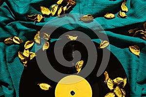 Layout of LP vinyl record on a cyan silk or saten fabric with yellow rose patels on it.  Old vintage record photo