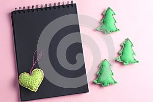Layout for Merry Christmas to-do list. black notebook and toys made by hand from felt on a pink background.