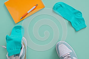 Layout of socks, sneakers, pen and notepad. Turquoise background