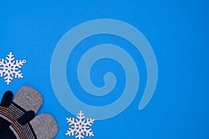 Layout of warm winter children's gloves and snowflakes on a blue background.The concept of winter outdoor recreation