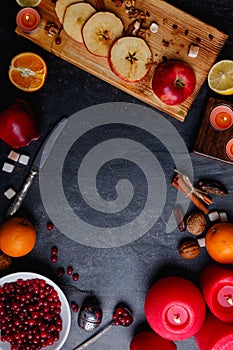 Layouts from slices of apples, a plate with cranberries, next orange and lemon, and burning candles. View from above.