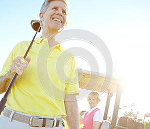 Lazy afternoon of golf. Low angle shot of a handsome older golfer standing in front of a golf cart with his golfing