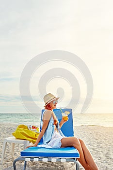 Lazy beachy, summer days. an attractive young woman lounging on the beach and enjoying a cocktail.