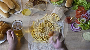 Lazy fat man eating greasy french fries and drinking beer, pernicious habits