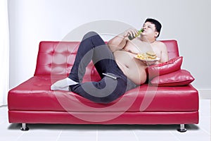 Lazy fat man reclining on couch