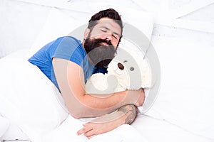 Lazy hipster relax in bedroom. good night and sweet dreams. bearded man teddy bear in bed. plush toy concept. happy