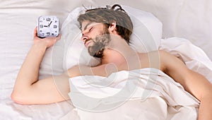 Lazy man happy waking up in the bed rising hands in the morning with fresh feeling relaxed. Man eyes are closed with