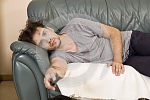 A young man watches television and changes channels while relaxing. photo