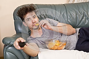 Lazy man with the remote and chips on the couch