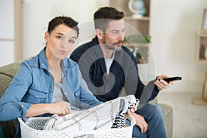 lazy man with remote control and wife with laundry basket