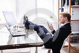 Lazy Man Using Phone At Work Desk
