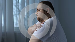 Lazy obese man exercising shoulder muscles, rheumatology disorder, lack of sport