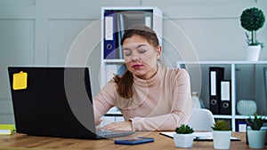 Lazy office girl typing on laptop and lying on table to sleep