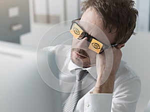 Lazy office worker wearing sticky notes over his glasses